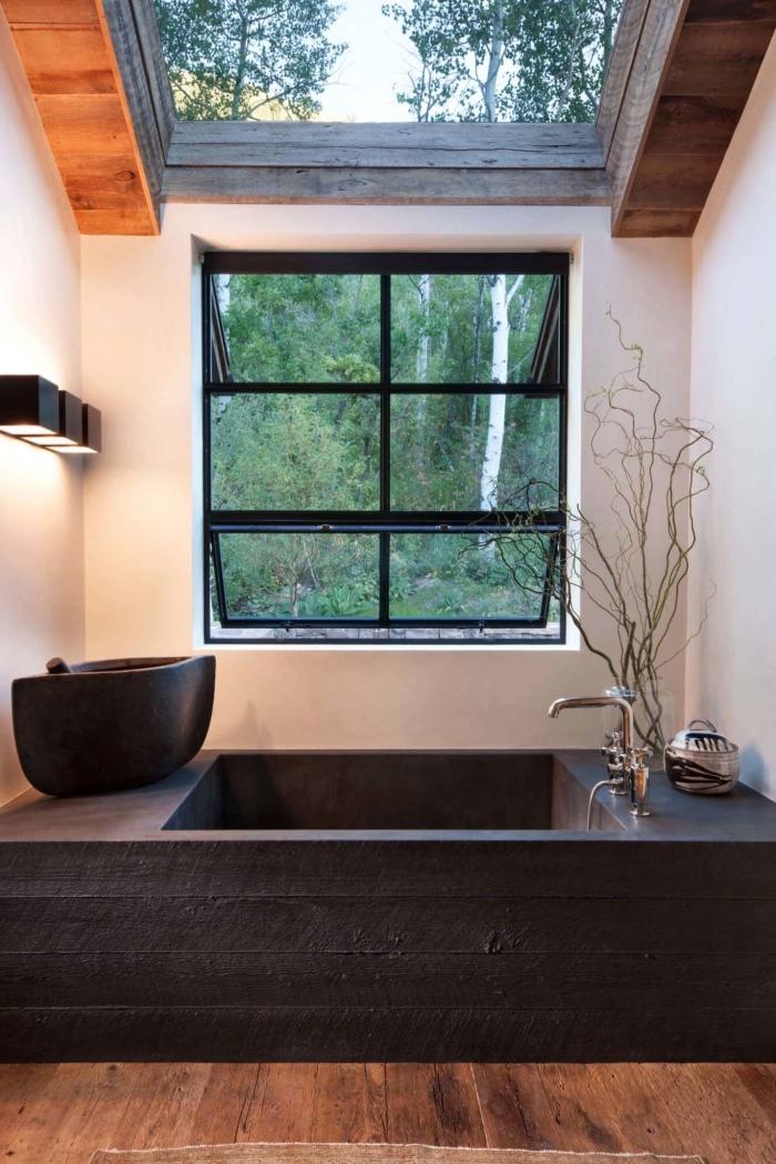 idée deco salle de bain zen avec plancher en bois et murs blancs aménagée avec baignoire et lavabo en noir