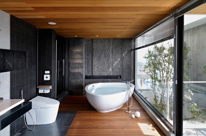 comment décorer une salle de bain zen avec carrelage mural en noir, salle de bain avec plafond et plancher en bois aux murs noirs