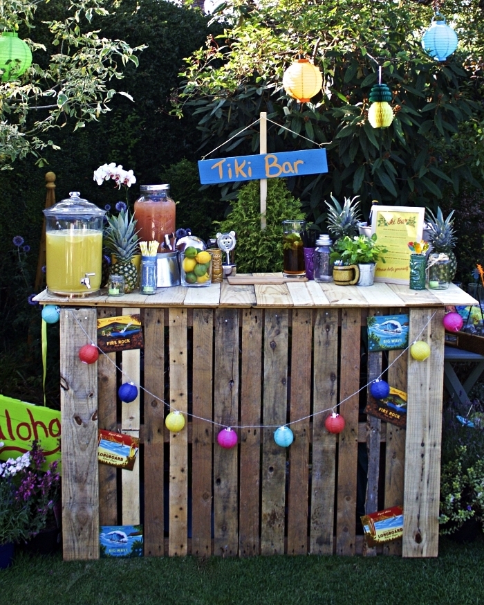 deco bar guinguette avec bonbonnières à jus, ananas, guirlande colorée et lanternes en papier, fabriquer un tiki bar dans son jardin