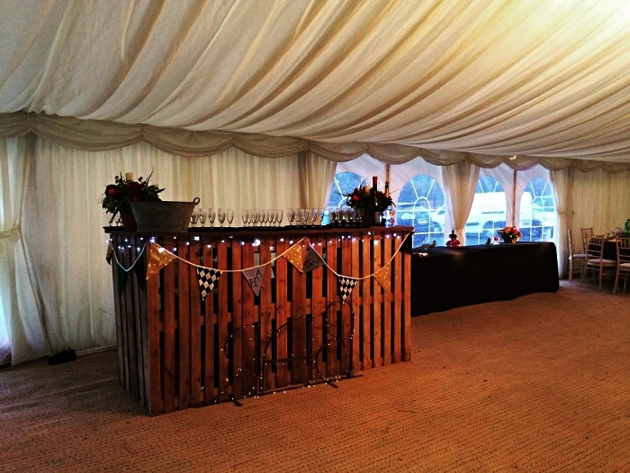 salle de réception mariage avec coin bar en bois récup décoré d'une guirlande à fanions, fabriquer un bar à boissons avec des palettes