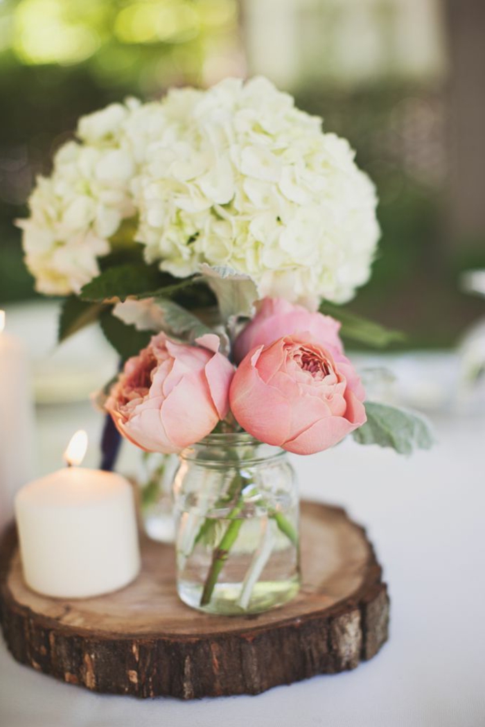 rondin de bois avec deux vases et une bougie allumée, décoration table romantique avec roses et hortensias