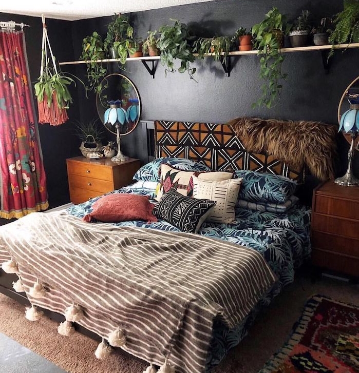 couleur mur noir, linge de lit tropical et hippie chic, tapis marron, étagère surchargée de petits pots de fleurs, commode bois vintage, miroir rond, rideaux colorés