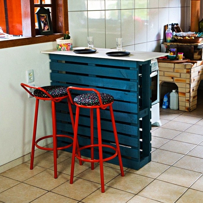 un bar de cuisine en palette récup repeinte en bleu canard, ilot cuisine palette recyclée avec deux tabourets de bar en métal rouge
