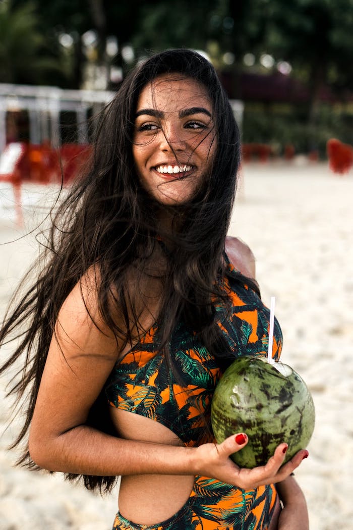 Fille souriante à longs cheveux brunes avec coco dans ses mains, plage photo, fond d'écran plage, image été, fond d'écran original