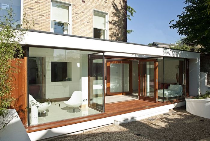 idee de design minimaliste d extenion vitrée avec lit et coin repos en fauteuils blancs, extension maison toit plat