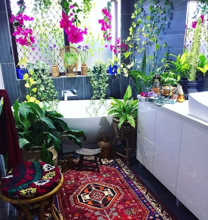 idee plante salle de bain, plusieurs espèces végétaux vertes et fuchsia, tapis oriental, meuble salle de bain blanc, carrelage gris salle de bain