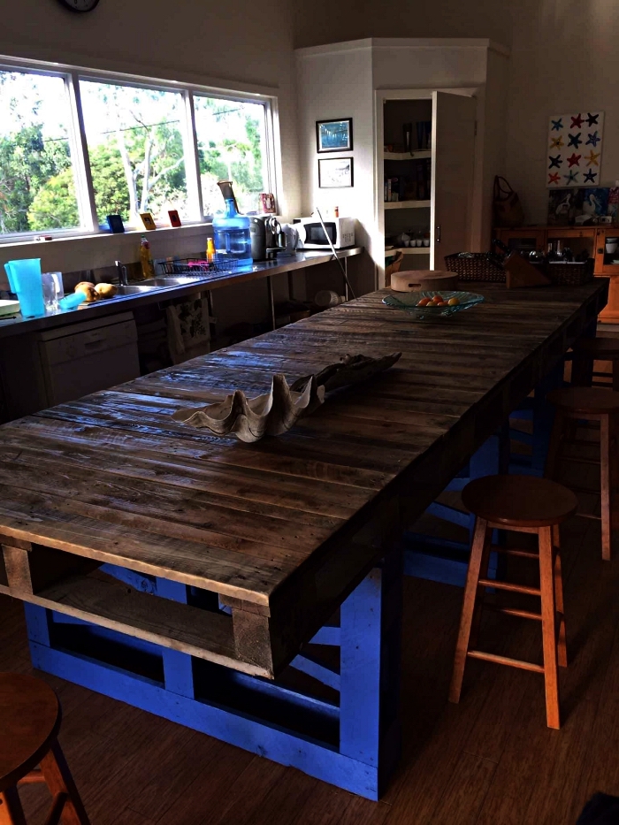une grande table en bois rustique avec plateau en palettes, ilot central palette