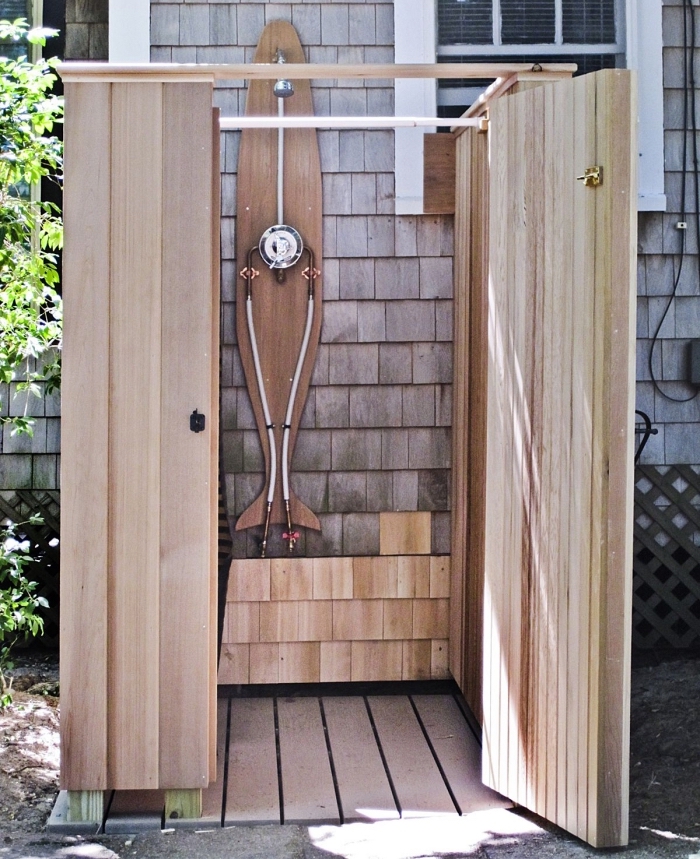 modèle de petite salle de bain dans le jardin avec receveur de douche en bois et pommeau de douche en inox