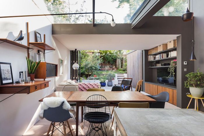 cuisine moderne qui s'ouvre sur un salon moderne abrité sous le toit d une extension avec canapé blanc, meuble tv bois et chaises