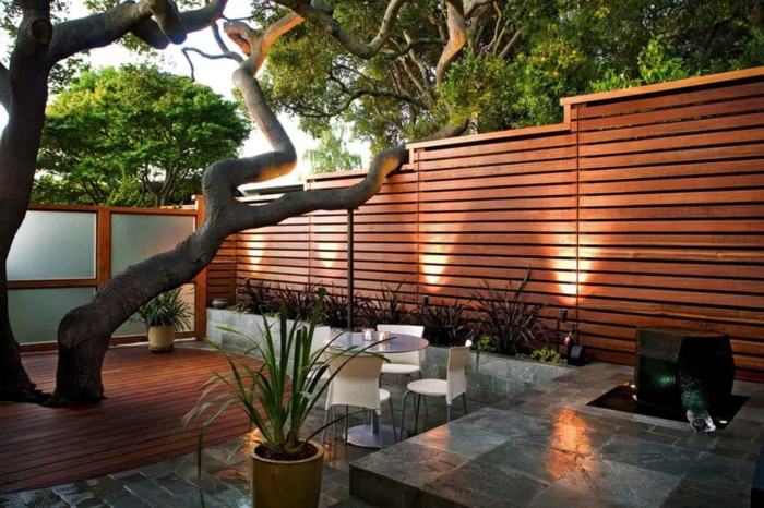palissade en bois, arbre, dallage et terrasse en bois, table ronde avec des chaises, parterre minimaliste, cloison japonaise