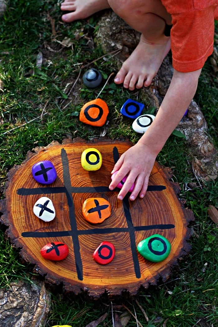 fabriquer un jeu de tic-tac-toe avec galets pions peints en couleurs différentes et un quadrillage sur un tronc d'arbre