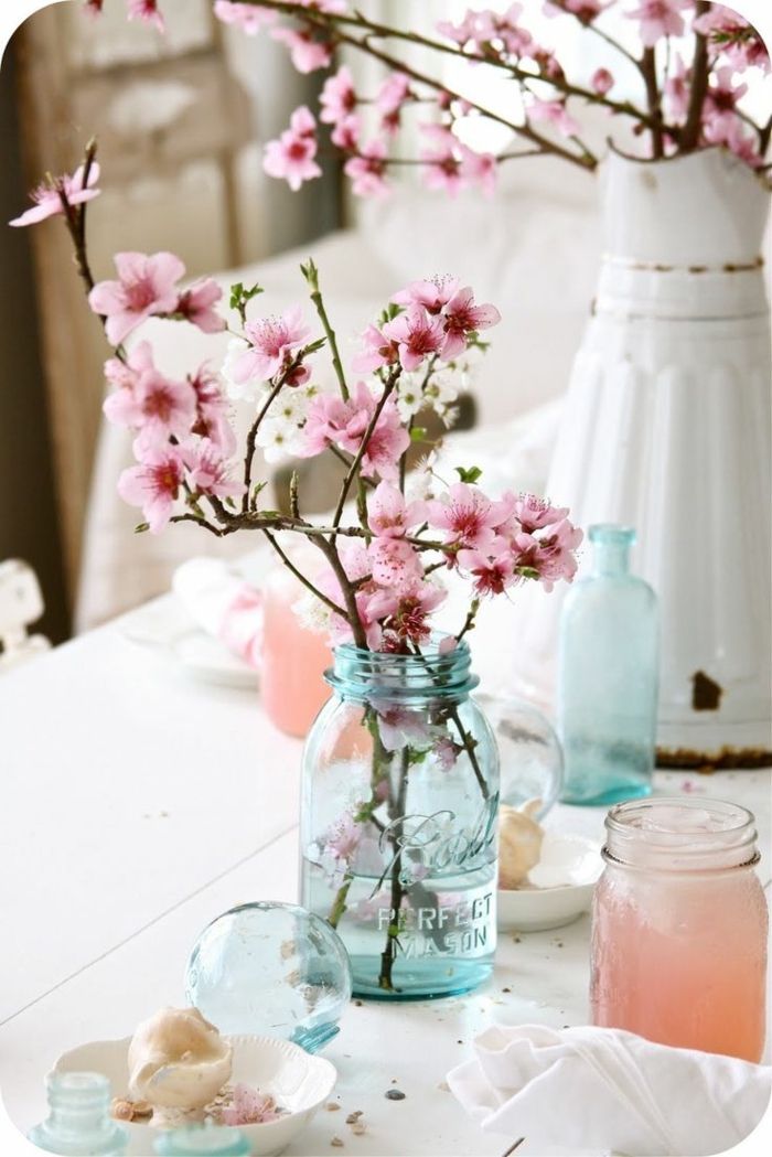 bocaux turquoises avec branches fleuries, carafe vintage blanche, bougies bricolées, idee deco table