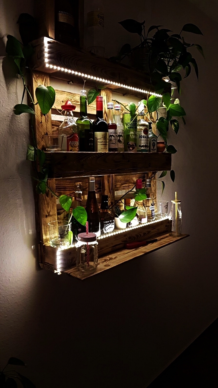 meuble de bar mural en palette pour ranger ses bouteilles d'alcool, deco palette de plantes vertes et d'une guirlande à led