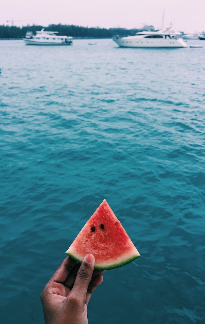 Tranche de pastèque rouge et vert en contrast avec la mer bleue, fond d'écran paysage d'été, la beauté de la nature en été 