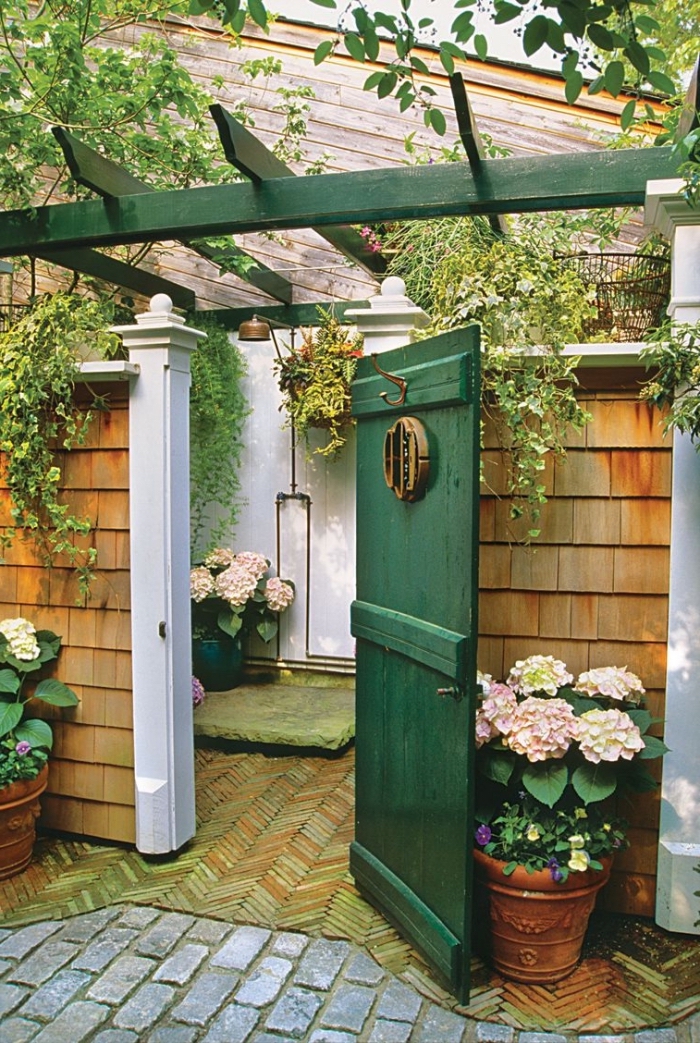 comment aménager une salle d'eau dans la cour arrière, exemple de salle de bain dans le jardin avec murs blancs et douche cuivre
