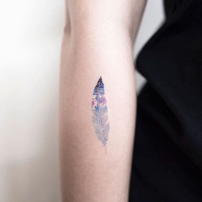tatouage plume en lilas et bleu, symbole indien, tatouage avant bras femme minimaliste et coloré