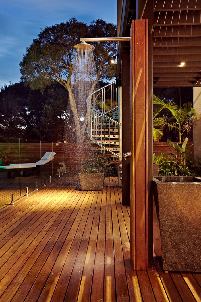 aménagement extérieur d'une maison moderne avec terrasse bois foncé, exemple de douche fixe sur colonne en bois marron