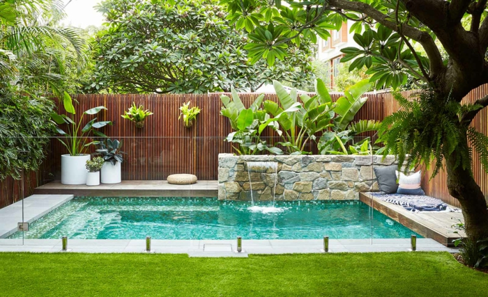 piscine avec escalier dans un jardin paysager magnifique, canisse bambou, muret en pierre naturelle, espace de détente, gazon