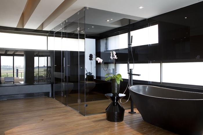décoration luxueuse salle de bain aux murs noirs avec grandes fenêtres et plancher en bois, modèle de baignoire noire autoportante