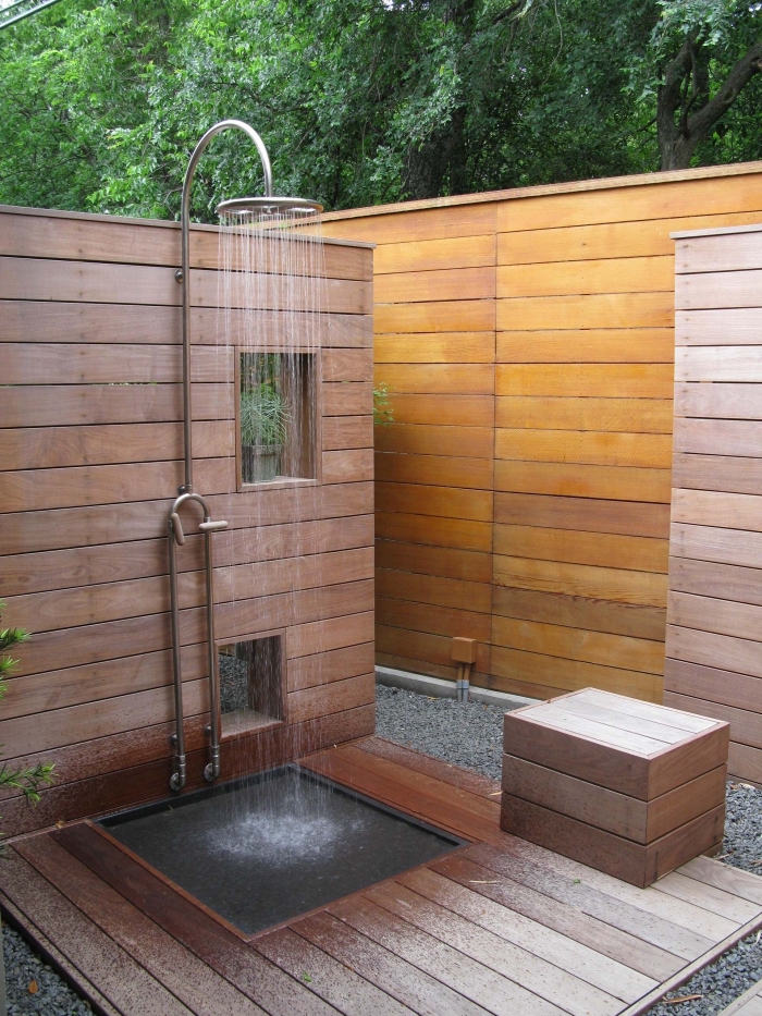 exemple de douche de jardin en inox et à effet pluie avec receveur béton, modèle salle d'eau extérieure en bois