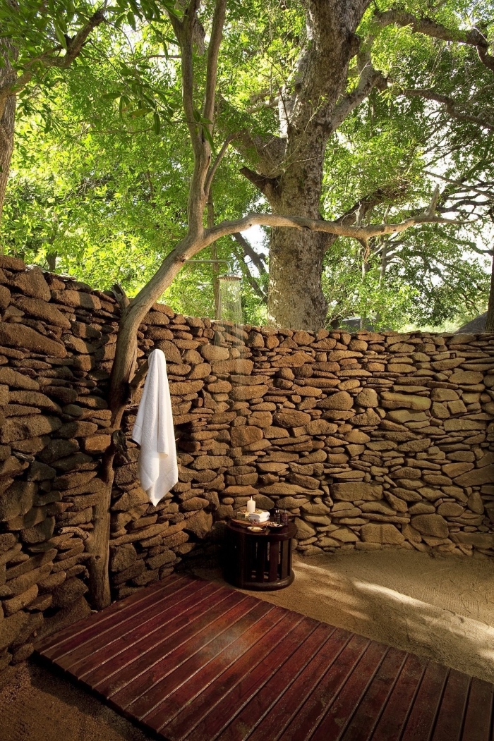 comment décorer un jardin de style zen aux murs en pierre avec terrasse en bois et sable, douche de jardin pluie