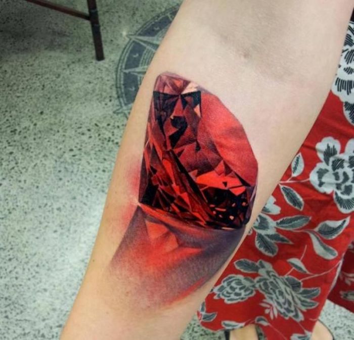 tatouage rubis, image de rubis rouge aux facettes, réflexion, tatouage femme en rouge et noir