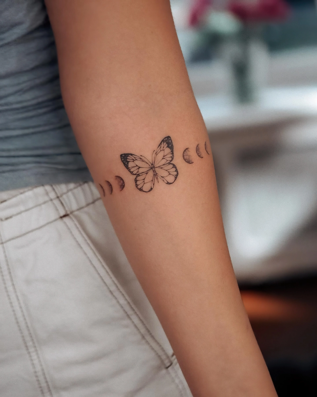 tatouage bras femme dessin papillon phases de la lune pantalon blanc debardeur