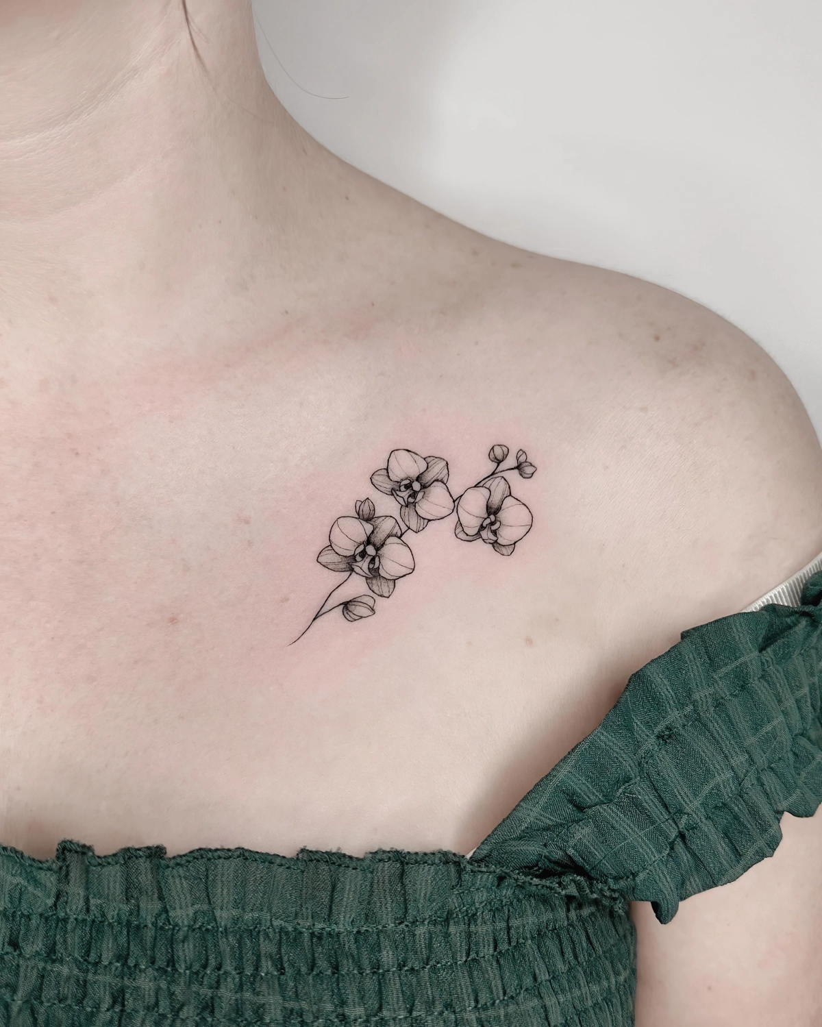 tatouage femme blouse vert fonce dessin fleurs tiges orchidee art corporel