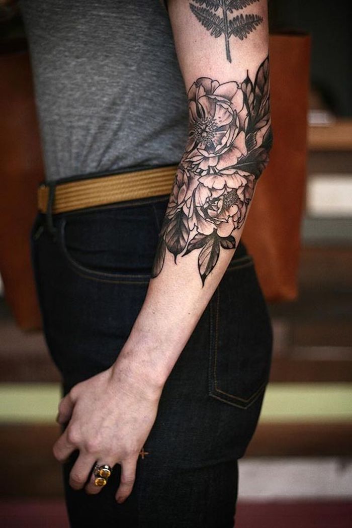 fleurs monochromes tatouées sur le bras, jeans, top gris, tatouage aux motifs végétaux 