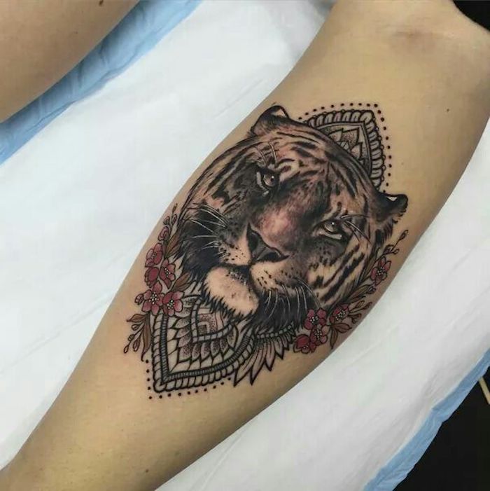 tatouage lion et fleurs au mollet, animal totem, tatouage symbolisant la force et le courage