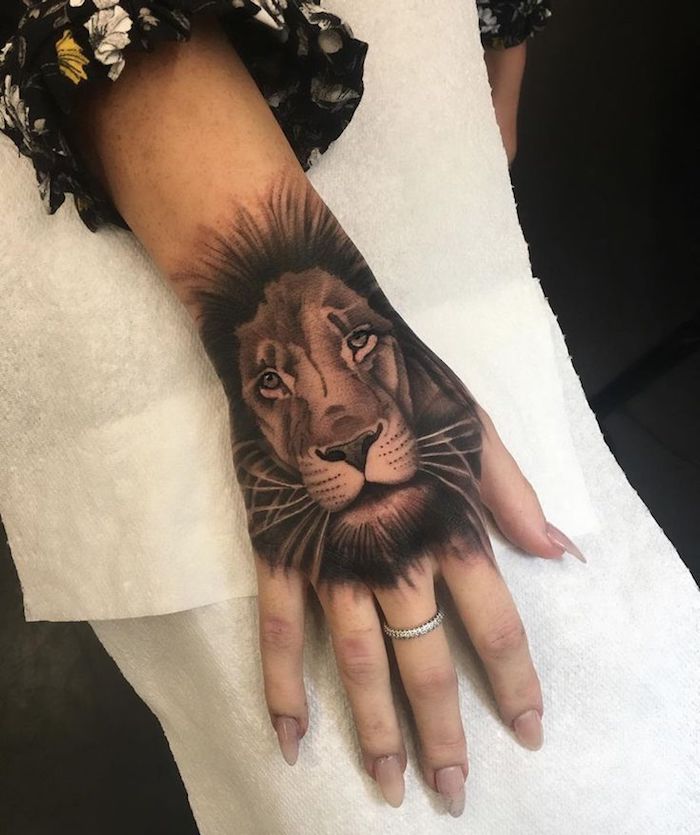 tatouage lion au poignet, tatouage main femme, bague en argent, manches de chemise florale