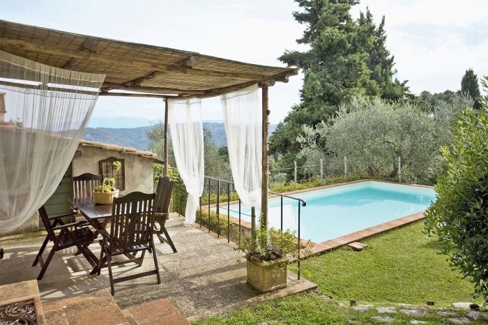 terrasse bétonnée avec toit en bambou et rideaux blancs aménagée avec meubles en bois foncé, amenagement autour piscine photos