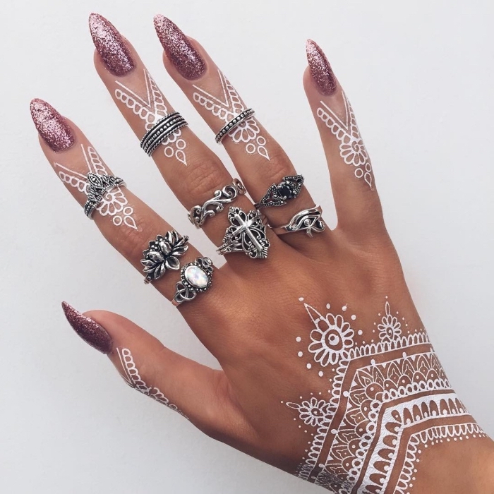 manucure ongles longs à vernis glitter rose, tatouage blanc temporaire sur main et doigts aux motifs ethniques