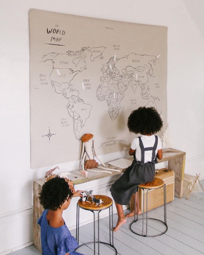 Enfants mignons qui jouent dans leurs chambre avec petit coin bureau diy de banc en bois, plan du monde gris dessiné par eux a feutre noir
