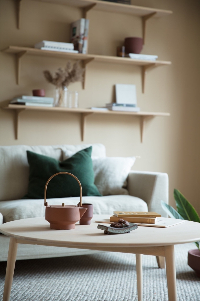 design salon aux murs de peinture beige sable avec meubles en bois clair, objets décoratifs de nuances de vert