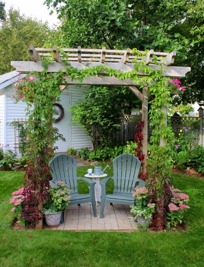 amenagement jardin paysager dans une cour arrière, déco arc en bois avec chaises grises et petite table ronde