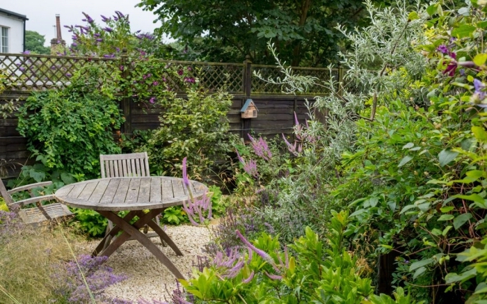 exemple de petit jardin avec galets et plantes vertes aménagé avec coin de repos en table et chaises pliantes bois