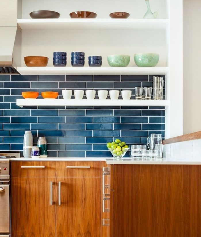 cuisine bleu, bois et blanc avec des étagères blanches surchargées de vaisselle et meuble bas bois