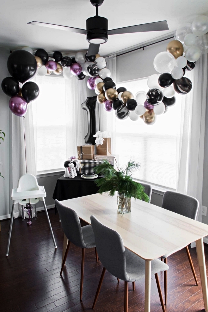 décoration anniversaire 1 de style minimaliste en noir et blanc avec une simple arche de ballons et un ballon chiffre 