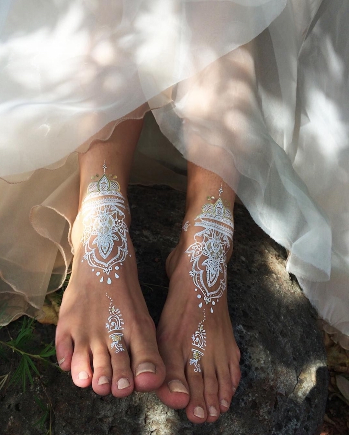exemple de tatouage bohème sur pieds à effet, modèle de tattoo henné en blanc et argent aux motifs ethniques