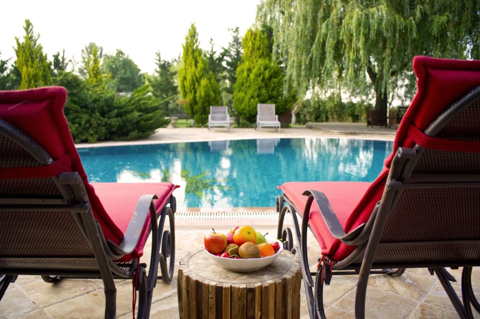 modèle de transat piscine en fer forgé avec housse rouge, deco piscine avec terrasse en dalles et meubles en fer