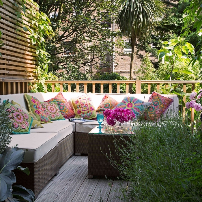 comment aménager son jardin, petit espace extérieur avec revêtement de sol en bois et meubles tressés foncés 