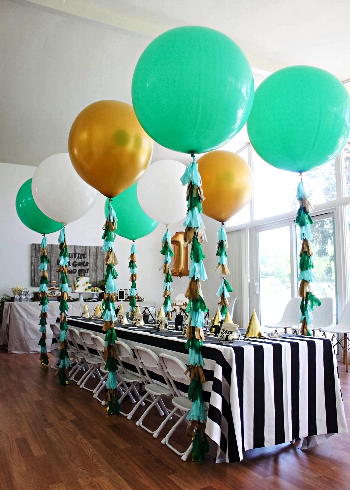 deco table anniversaire avec nappe à rayures noires et blanches, décor de ballons avec queues franges