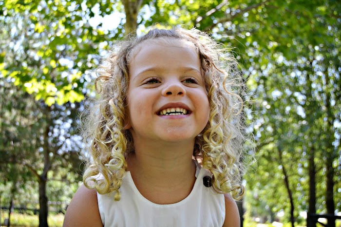 foret-ou-jardin-photo-sourire-beau-cheveux-crépus-fille-blonde-coiffure-simple-et-rapide-coiffure-petite-fille-coiffure-fillette Sourire grand, fille blonde, cheveux crépus, coiffure petite fille mariage, coiffure facile a faire enfant