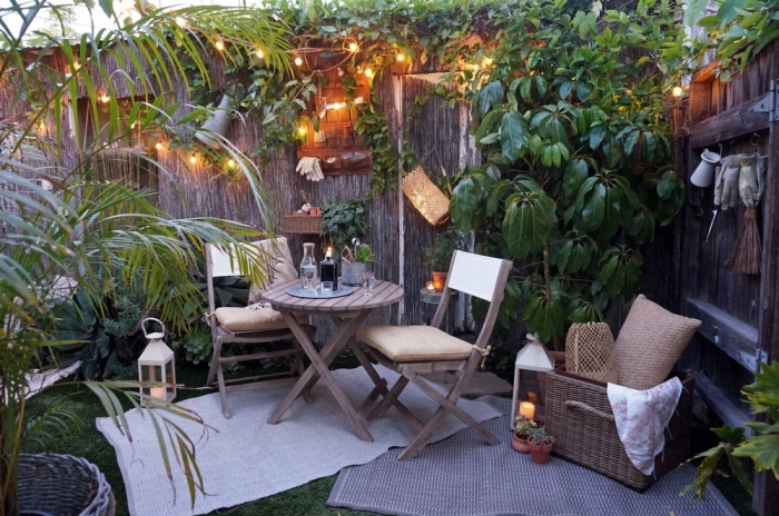 décoration jardin avec meubles en bois et guirlande lumineuse, idée aménagement terrasse et jardin photo avec clôture paille