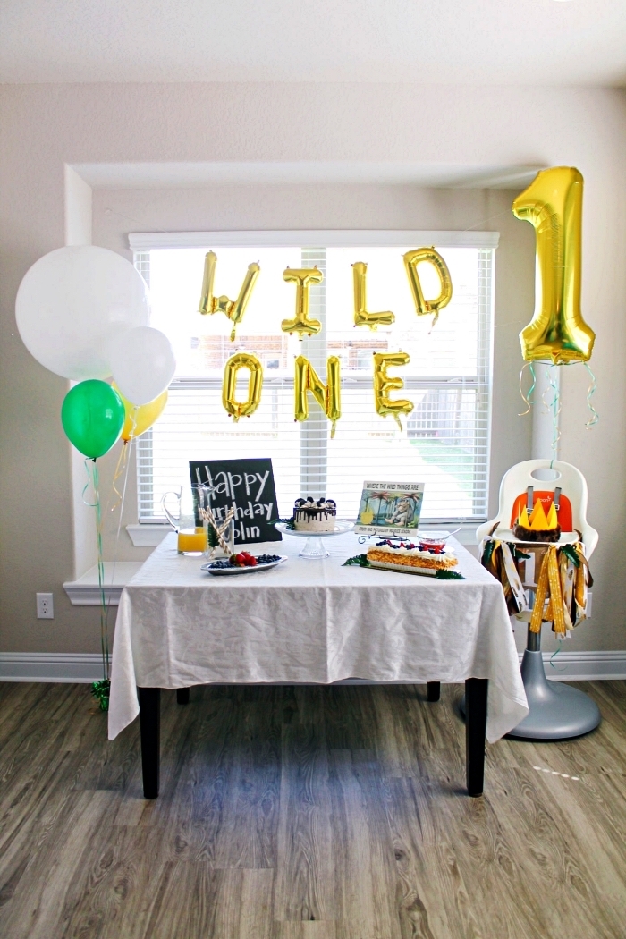 décoration anniversaire 1 an avec ballons mylar chiffres et lettres en or, chaise haute pour bébé décorée d'une guirlande à franges