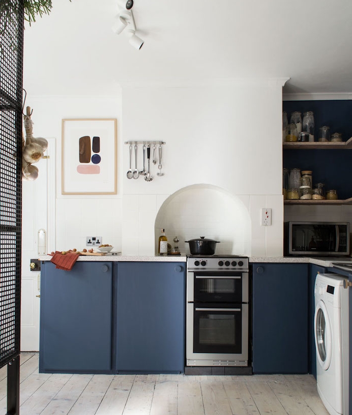 amenagement cuisine bleu nuit et blanc avec une niche murale rangements étagères, murs blancs, parquet vintage
