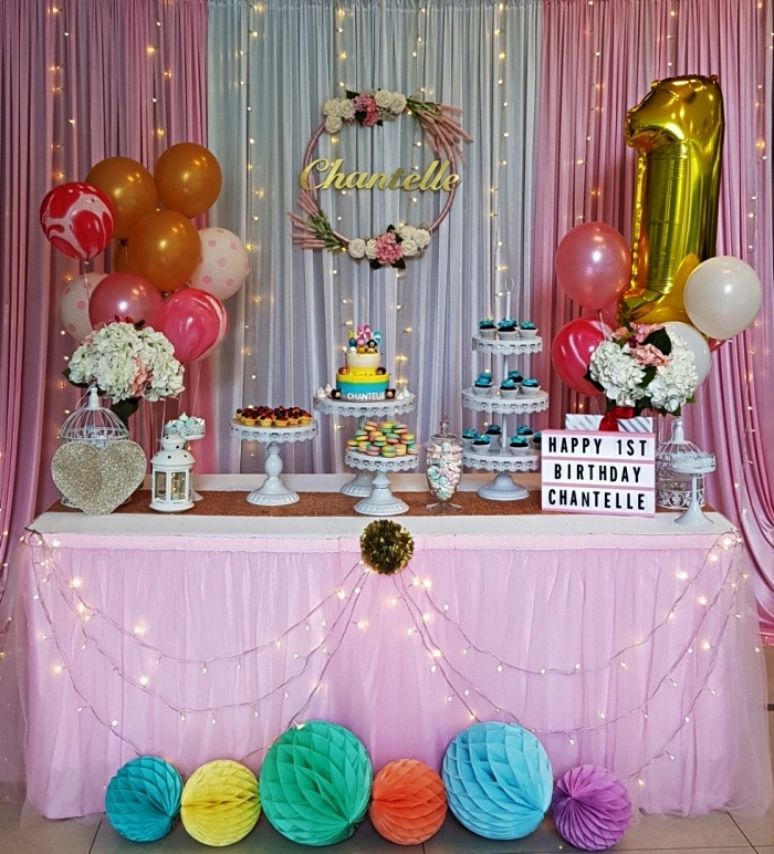 déco d'anniversaire girly en rose et or, sweet table d'anniversaire 1 a, décorée de ballons, guirlandes led, boules alvéolées et une jolie couronne de fleurs personnalisée