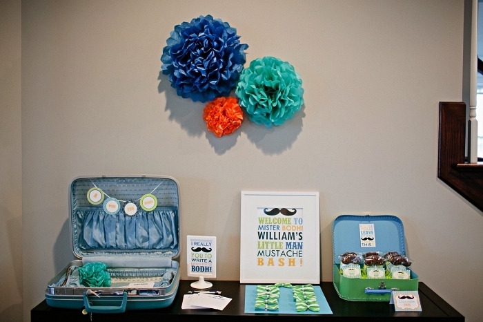 buffet gourmand sur le theme anniversaire moustache tout en bleu et vert, décoration à thème pour buffet gourmand avec présentoirs valises