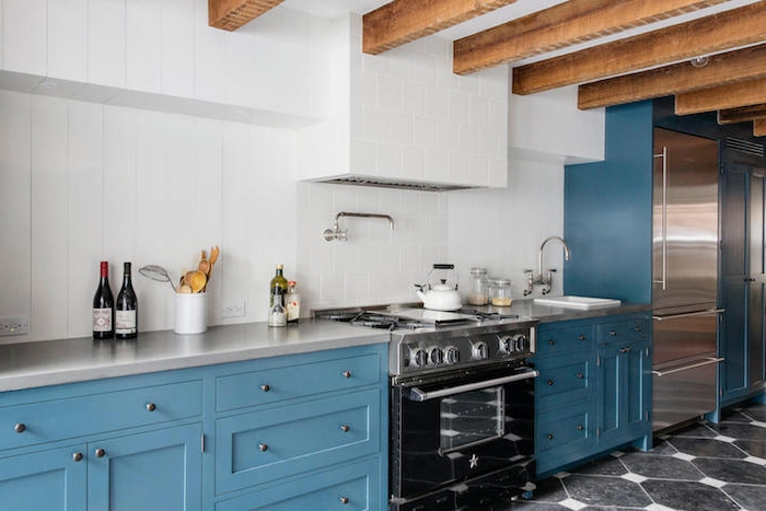 poutres apparentes dans une cuisine en bleu, carrelage mural blanc, plan de travail gris, electromenager noir et gris, cuisine vintage originale